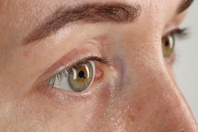 Woman with beautiful green eyes on light grey background, closeup