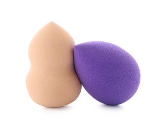 Photo of Beige and violet makeup sponges isolated on white