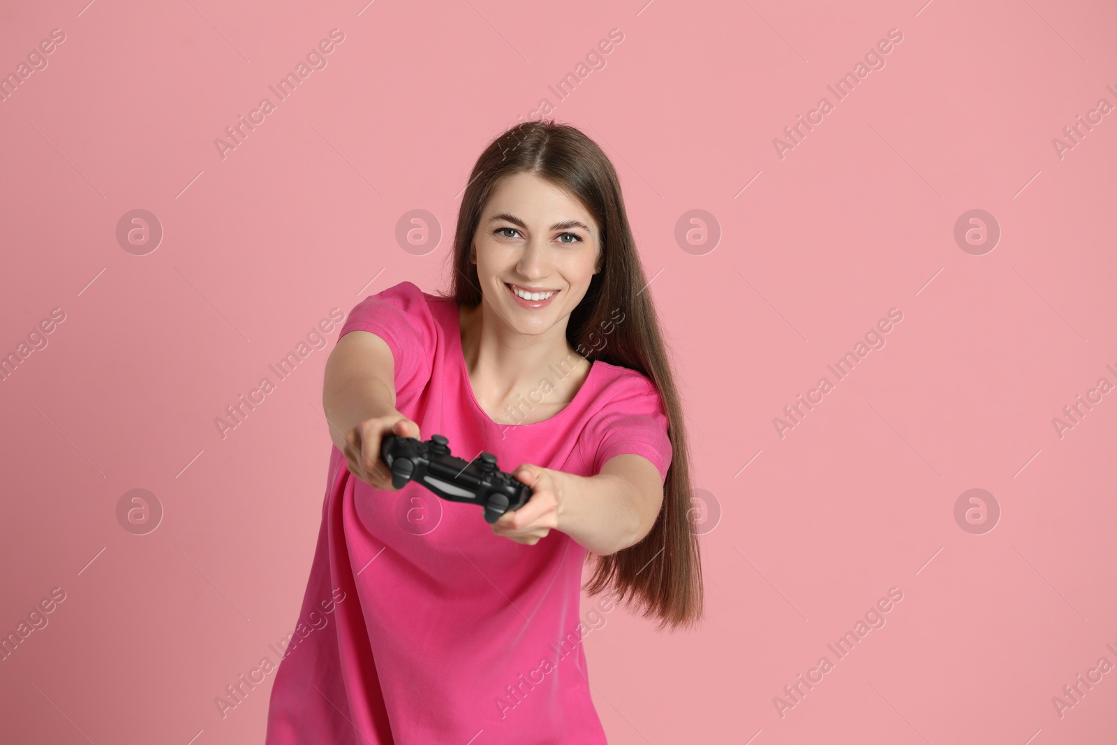 Photo of Happy woman playing video games with controller on pink background