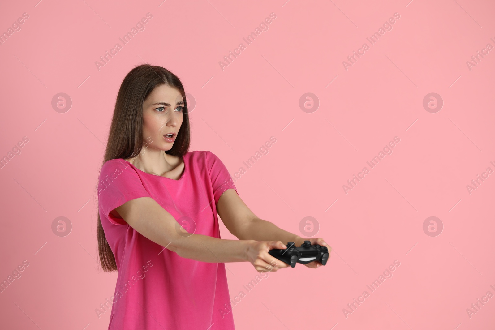 Photo of Woman playing video games with controller on pink background, space for text