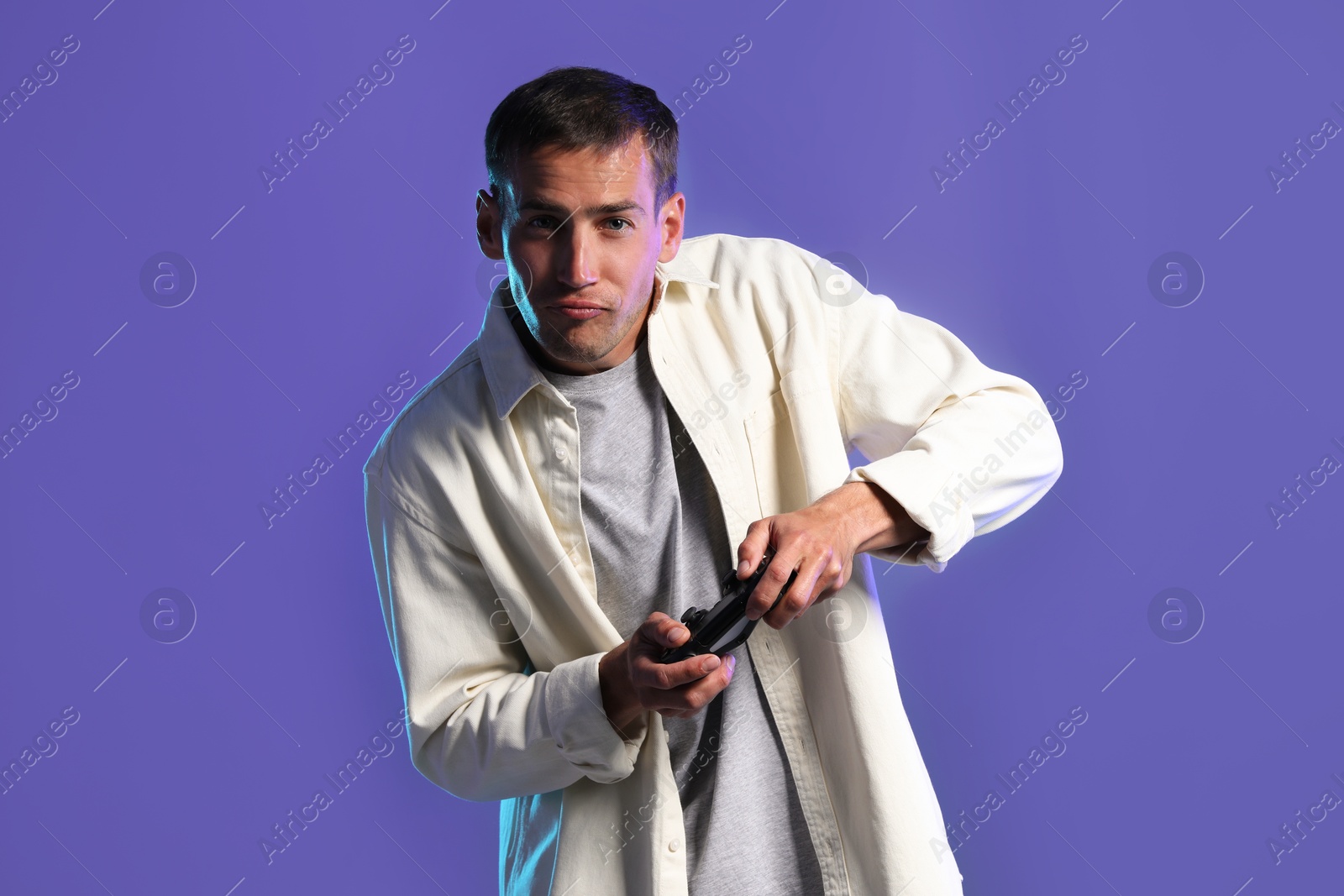 Photo of Man playing video games with controller on violet background