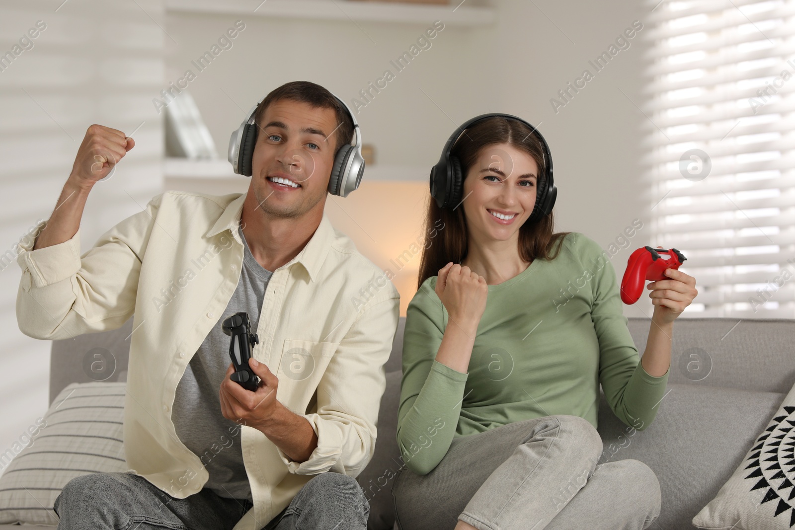 Photo of Couple playing video games with controllers at home