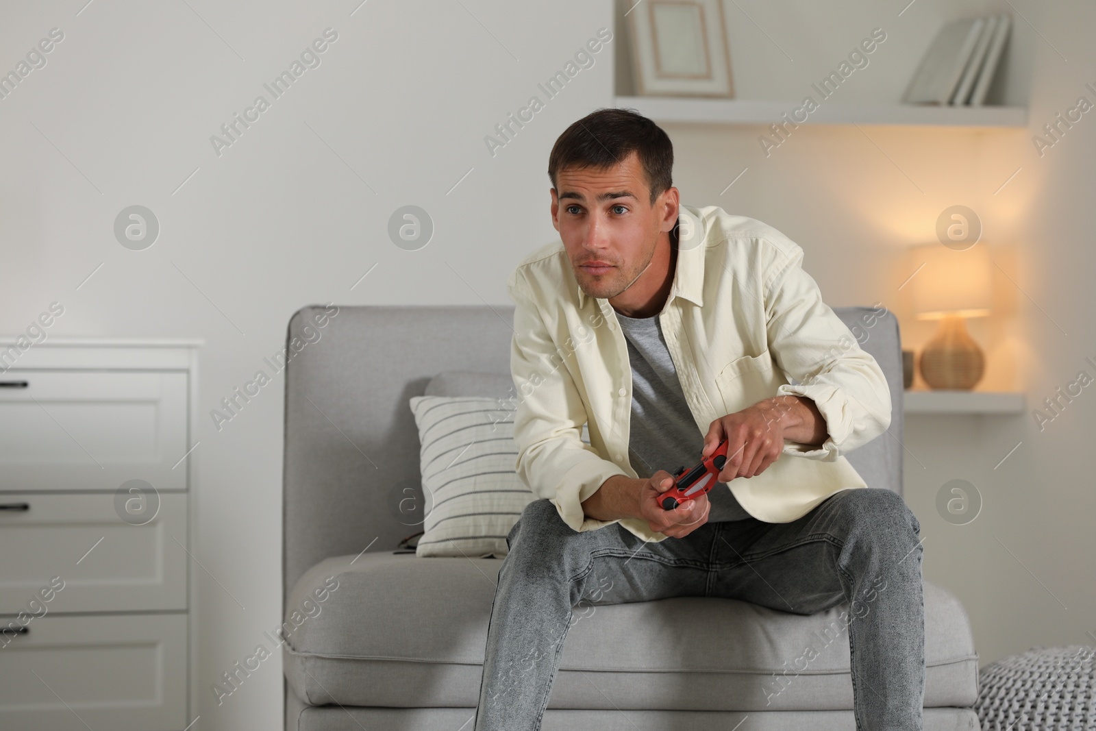 Photo of Man playing video games with joystick at home