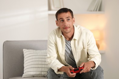 Photo of Man playing video games with joystick at home