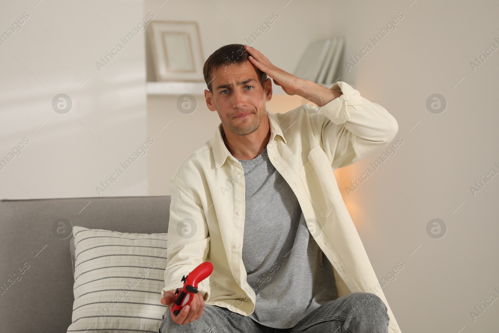 Photo of Emotional man playing video games with joystick at home