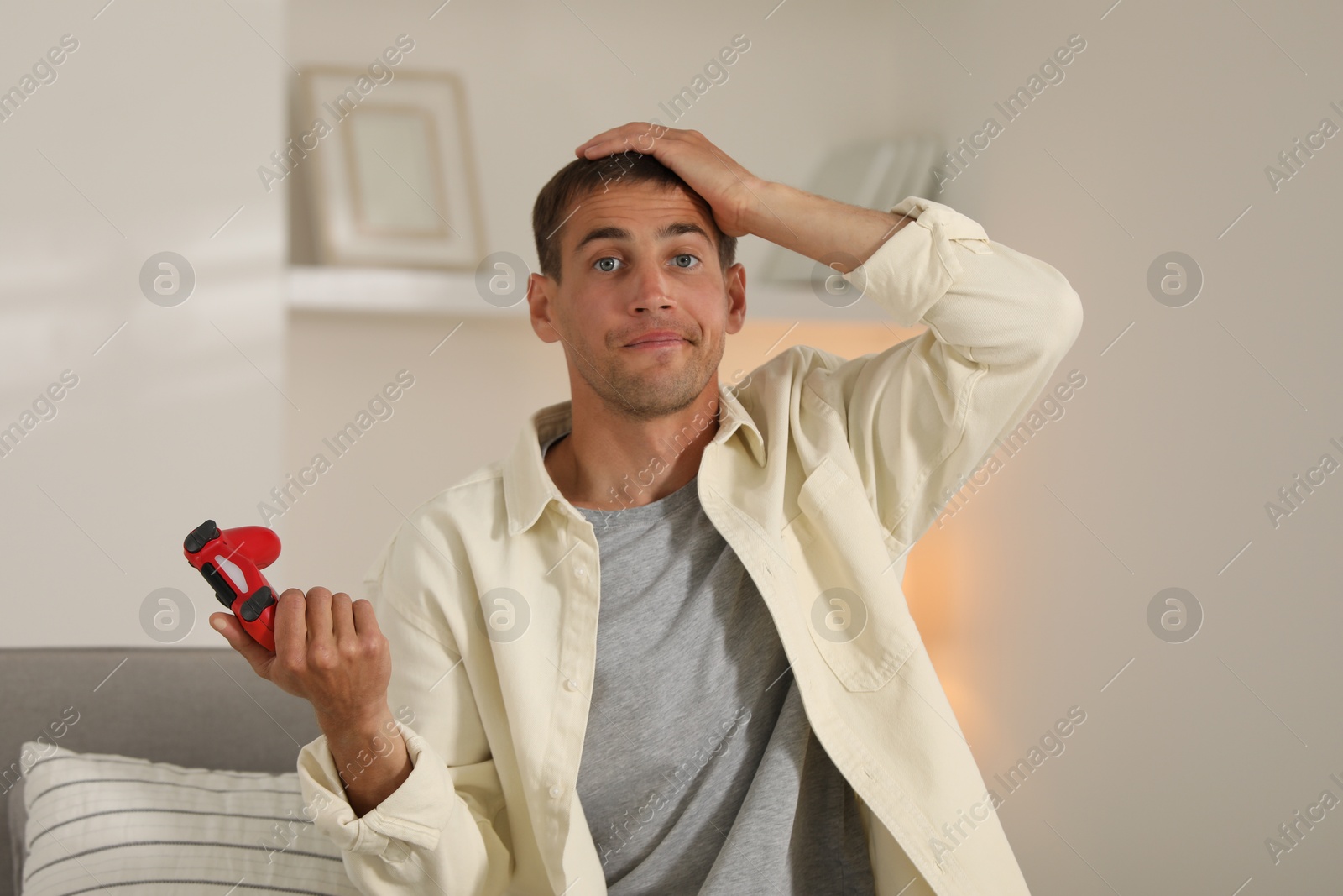 Photo of Emotional man playing video games with joystick at home