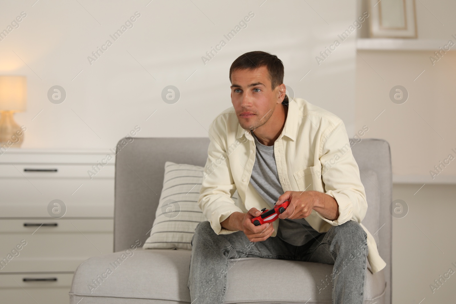 Photo of Man playing video games with joystick at home