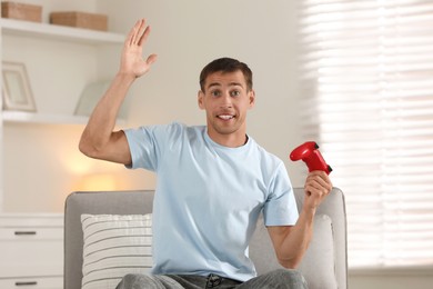 Emotional man playing video games with joystick at home