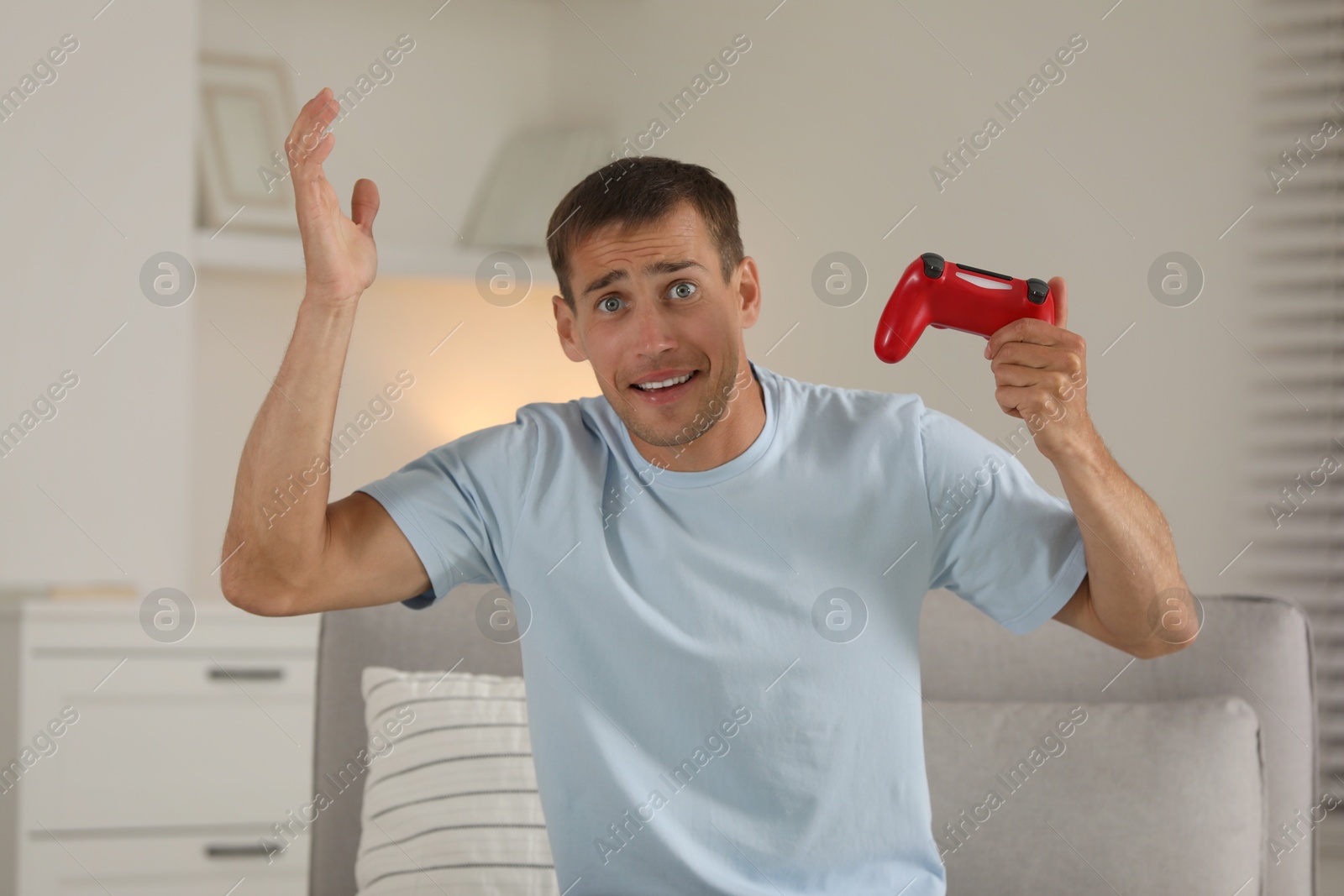 Photo of Emotional man playing video games with joystick at home