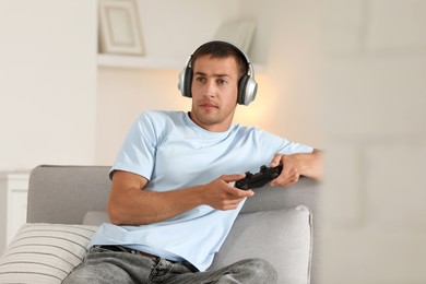 Photo of Man in headphones playing video games with joystick at home
