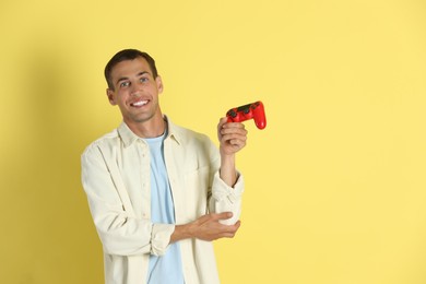 Photo of Happy man with controller on yellow background, space for text