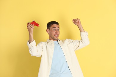 Surprised man with controller on yellow background