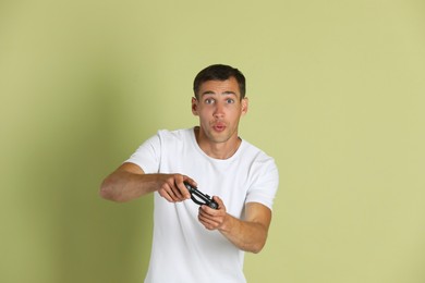Photo of Man playing video games with controller on light green background