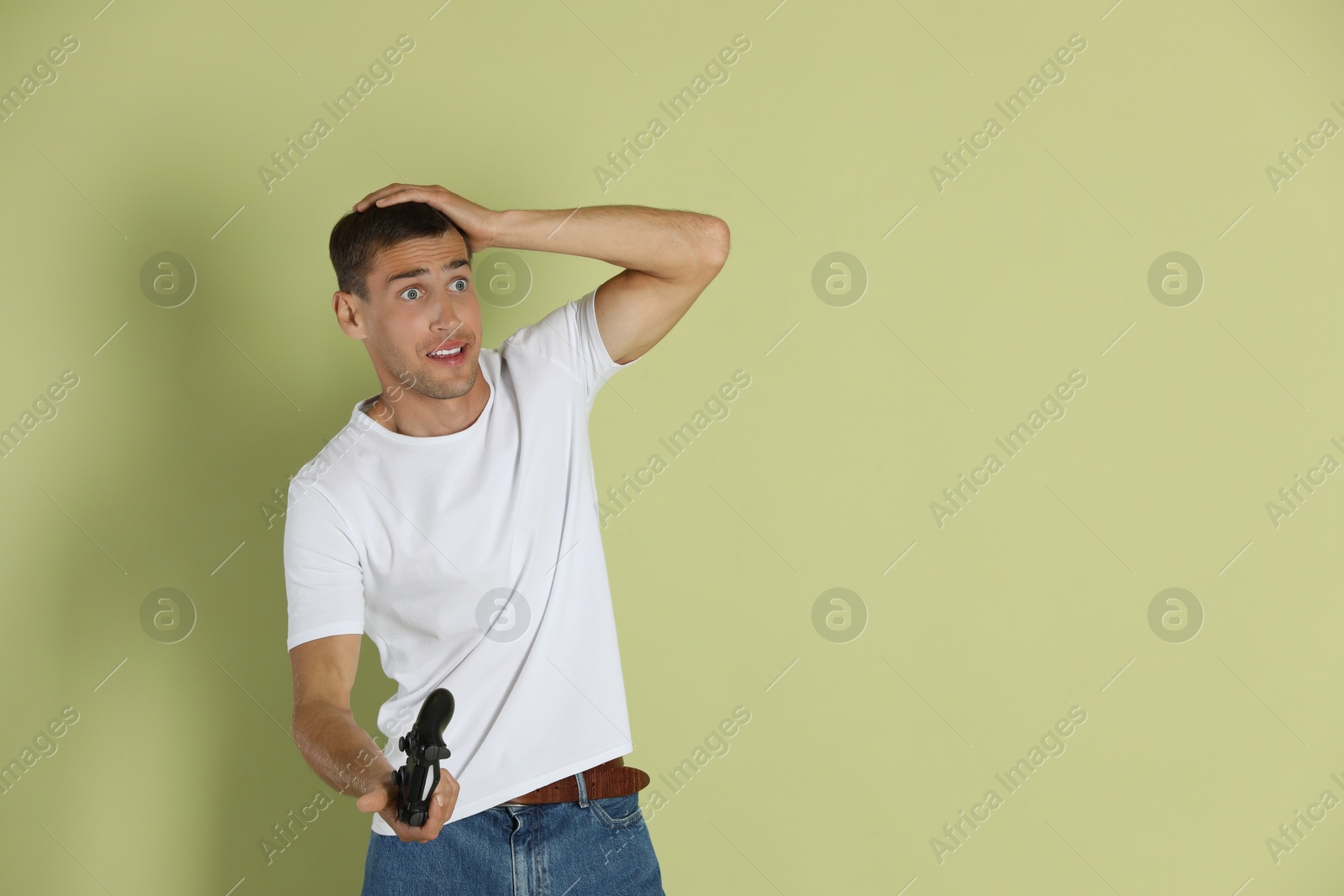 Photo of Emotional man with controller on light green background, space for text