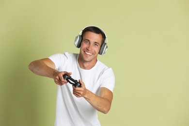 Photo of Happy man playing video games with controller on light green background, space for text
