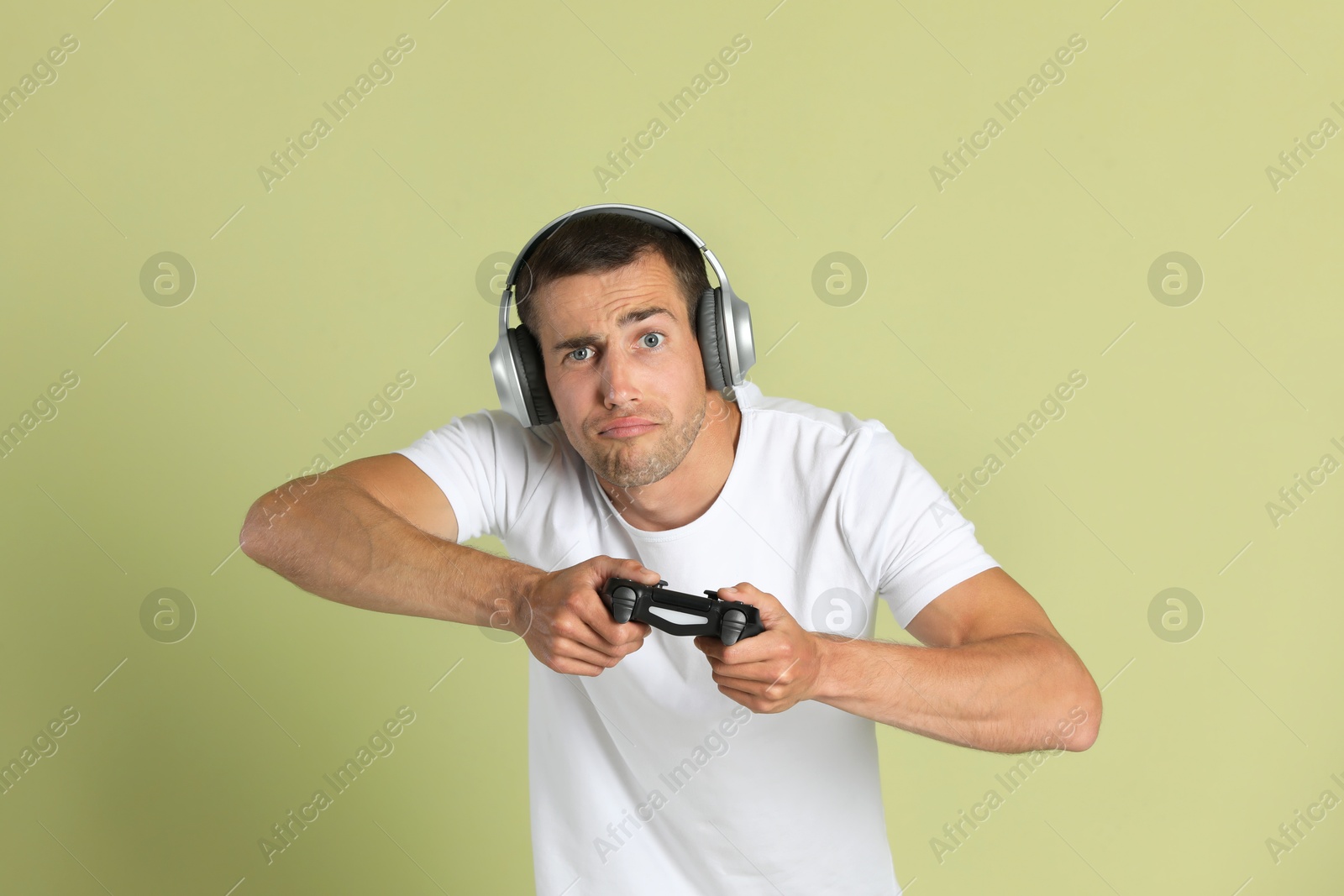 Photo of Man playing video games with controller on light green background