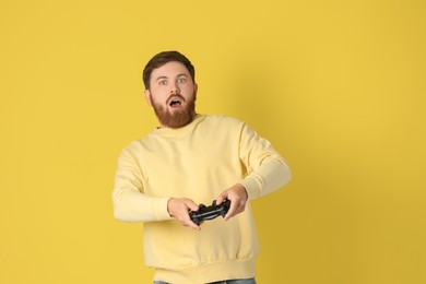 Photo of Surprised man playing video game with controller on pale yellow background