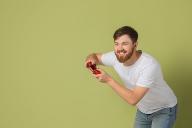 Happy man playing video game with controller on pale green background. Space for text