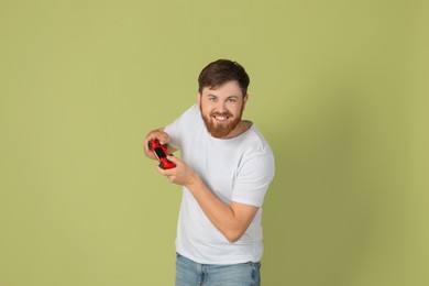 Happy man playing video game with controller on pale green background