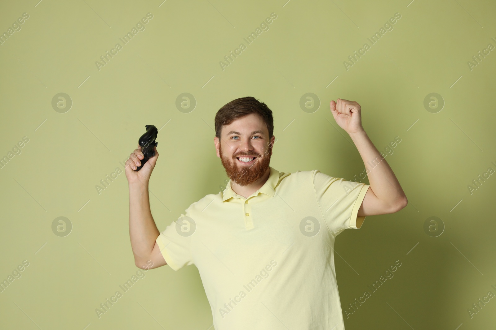 Photo of Happy man with game controller on pale green background