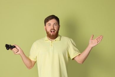 Photo of Emotional man with game controller on pale green background