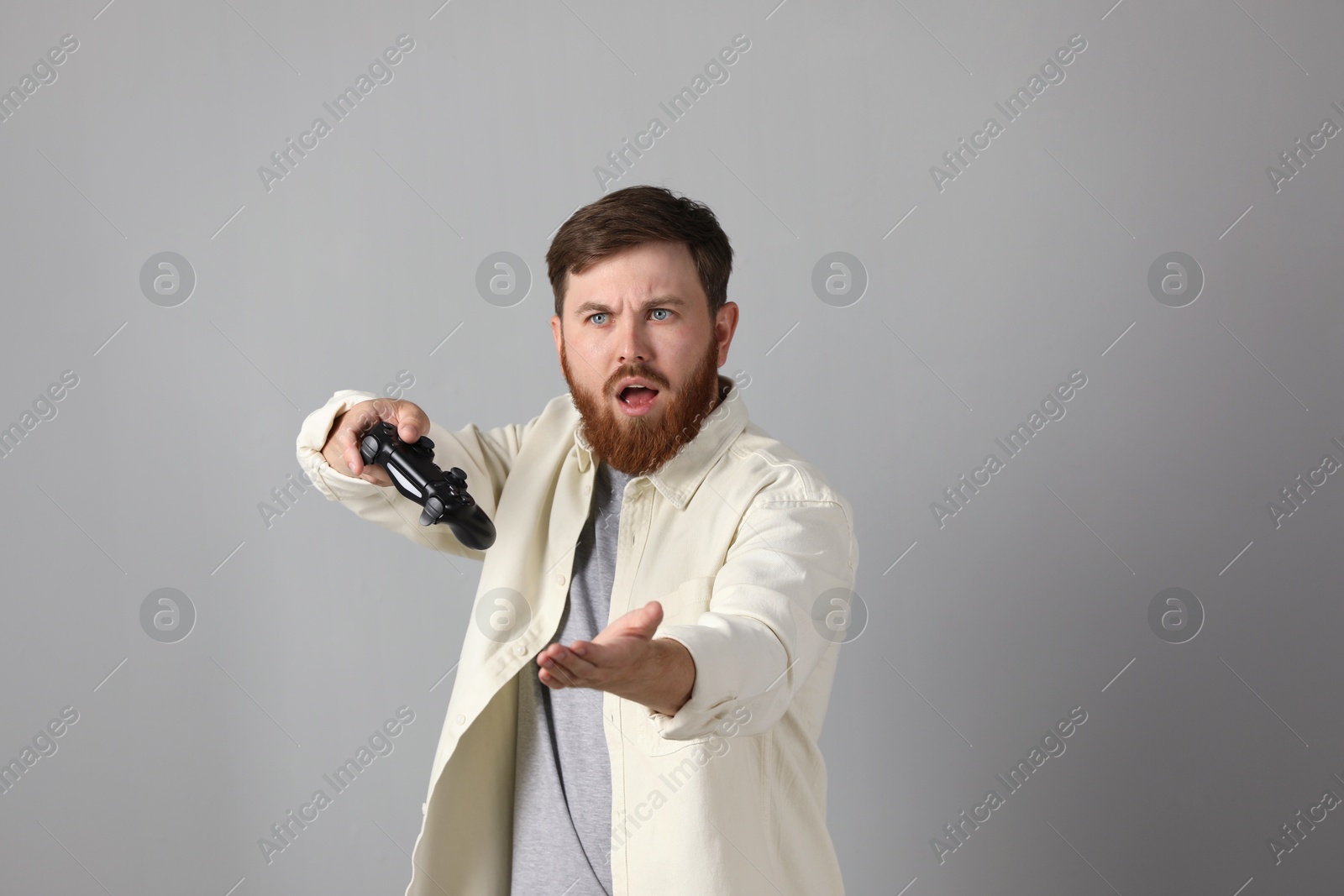 Photo of Surprised man with game controller on grey background