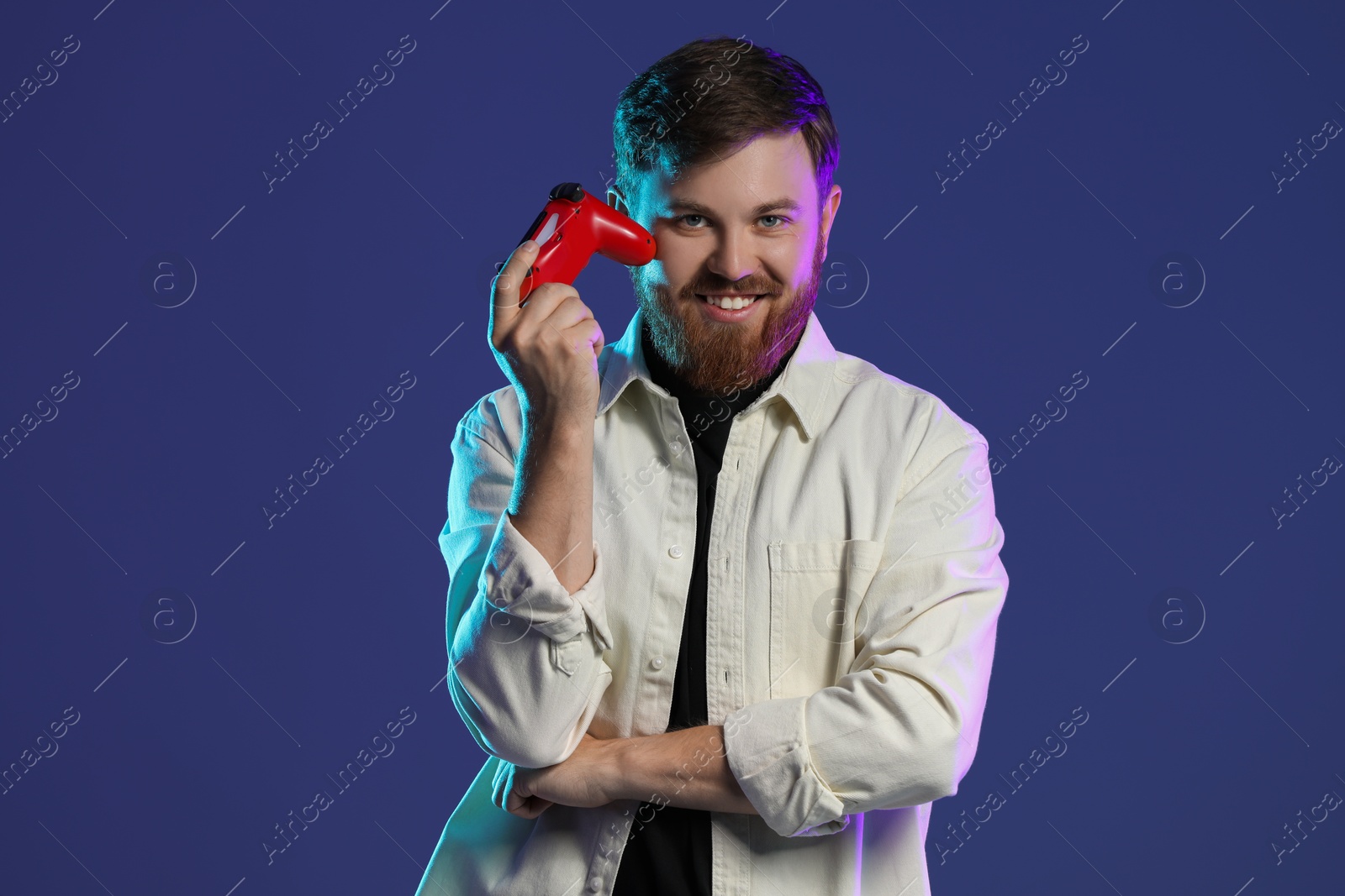 Photo of Happy man with game controller on dark blue background