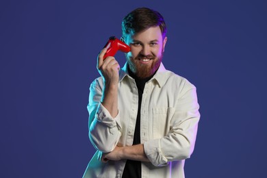 Happy man with game controller on dark blue background