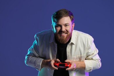 Photo of Happy man playing video game with controller on dark blue background