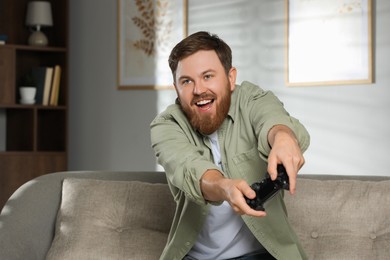 Happy man playing video game with controller at home