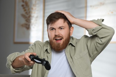 Confused man with game controller at home