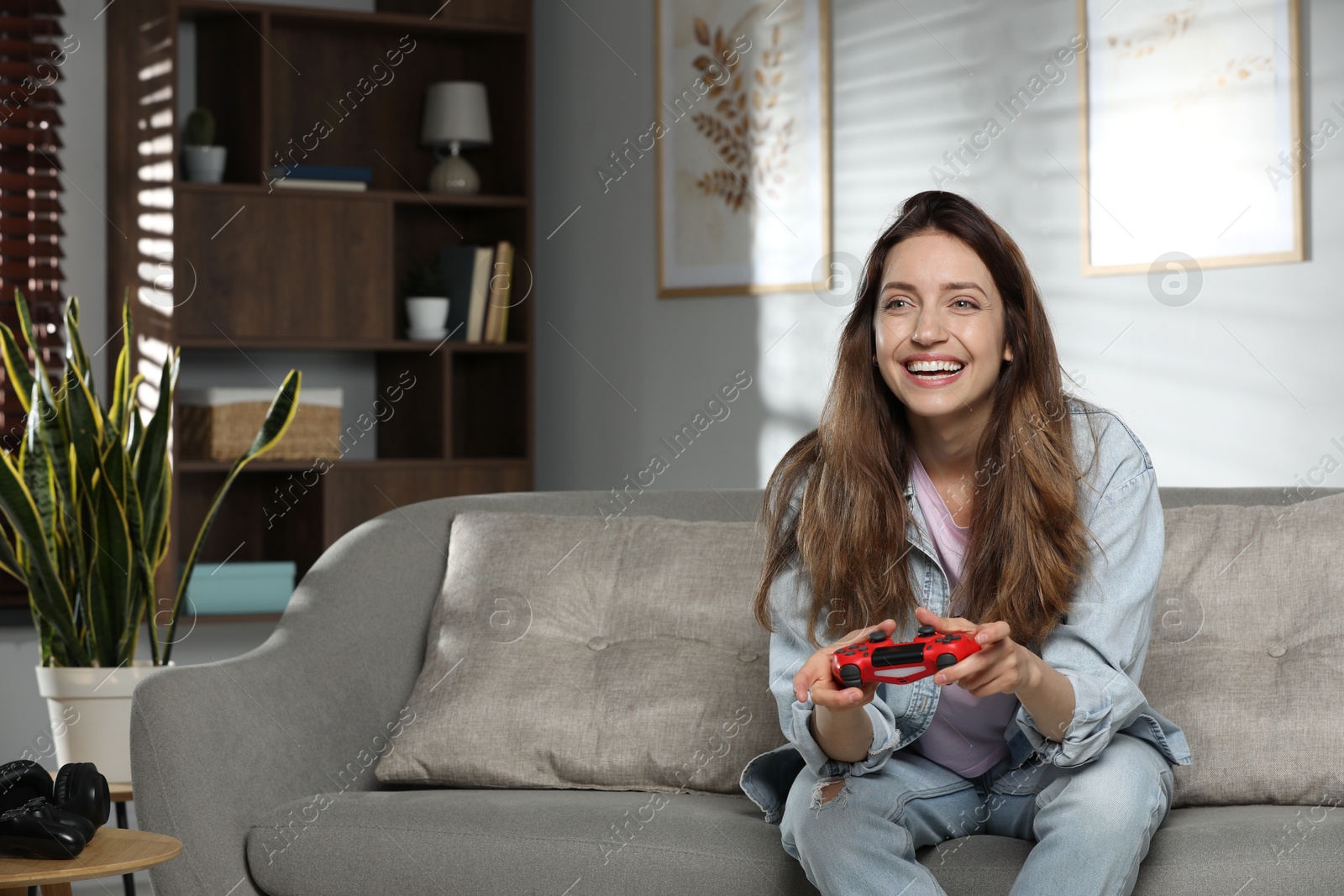 Photo of Happy woman playing video game with controller at home