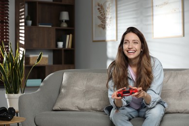 Photo of Happy woman playing video game with controller at home