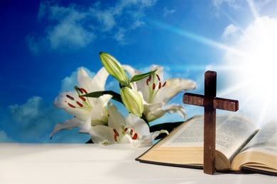 Image of Holy Bible, cross and lily flowers on table against blue sky. Religion of Christianity