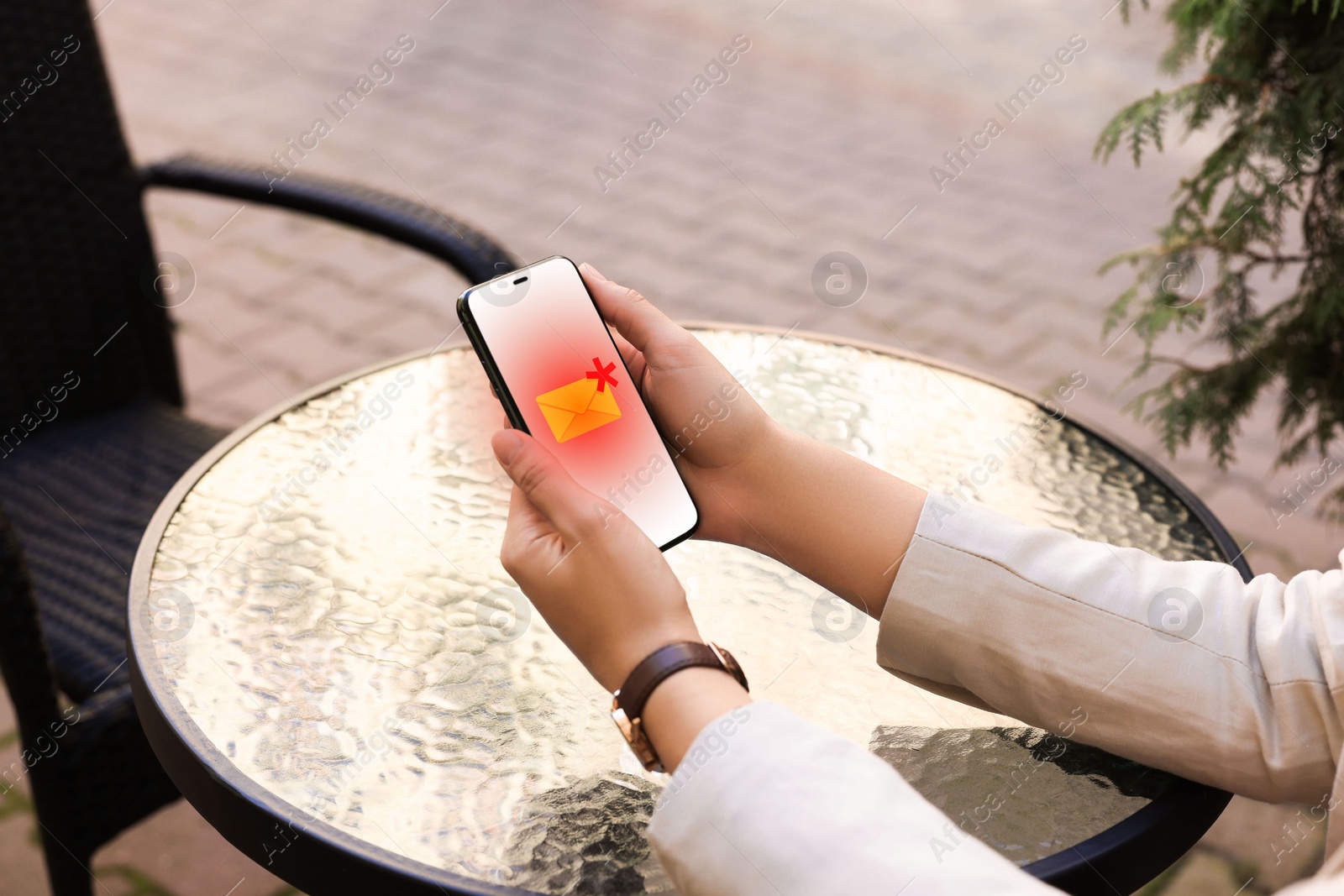 Image of Woman using smartphone at table outdoors, closeup. Spam message notification on device screen, illustration
