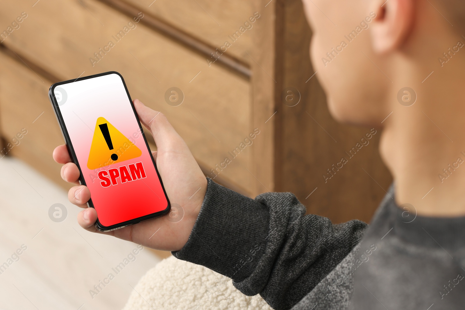 Image of Man using smartphone indoors, closeup. Spam message notification on device screen, illustration