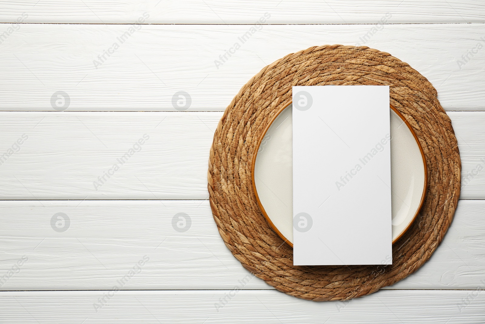 Photo of Empty menu and plate on white wooden table, top view. Mockup for design