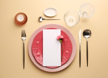 Photo of Empty menu, tableware, candle and floral decor on beige table, flat lay. Mockup for design