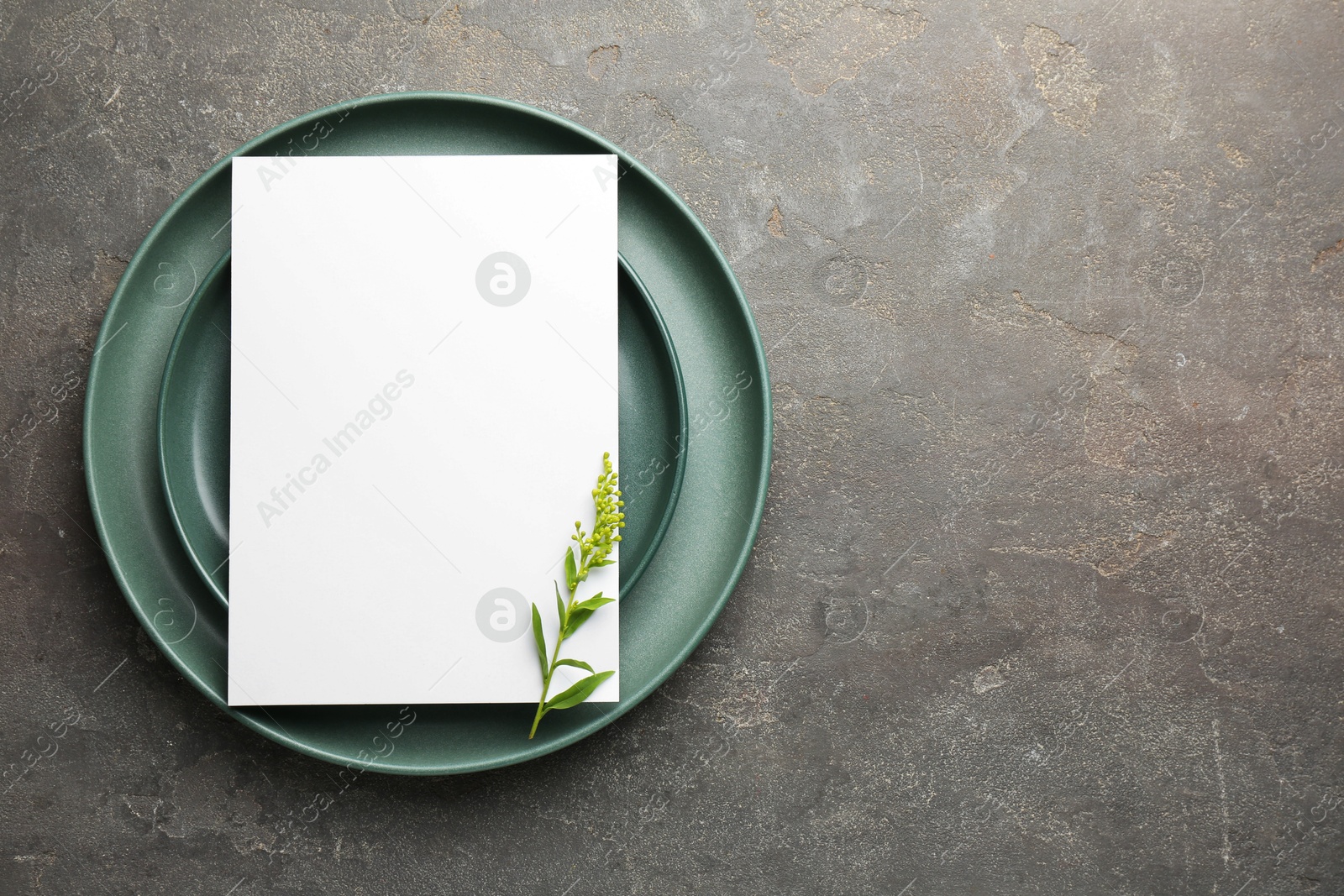 Photo of Empty menu, plates and floral decor on grey table, top view. Mockup for design