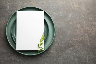 Photo of Empty menu, plates and floral decor on grey table, top view. Mockup for design