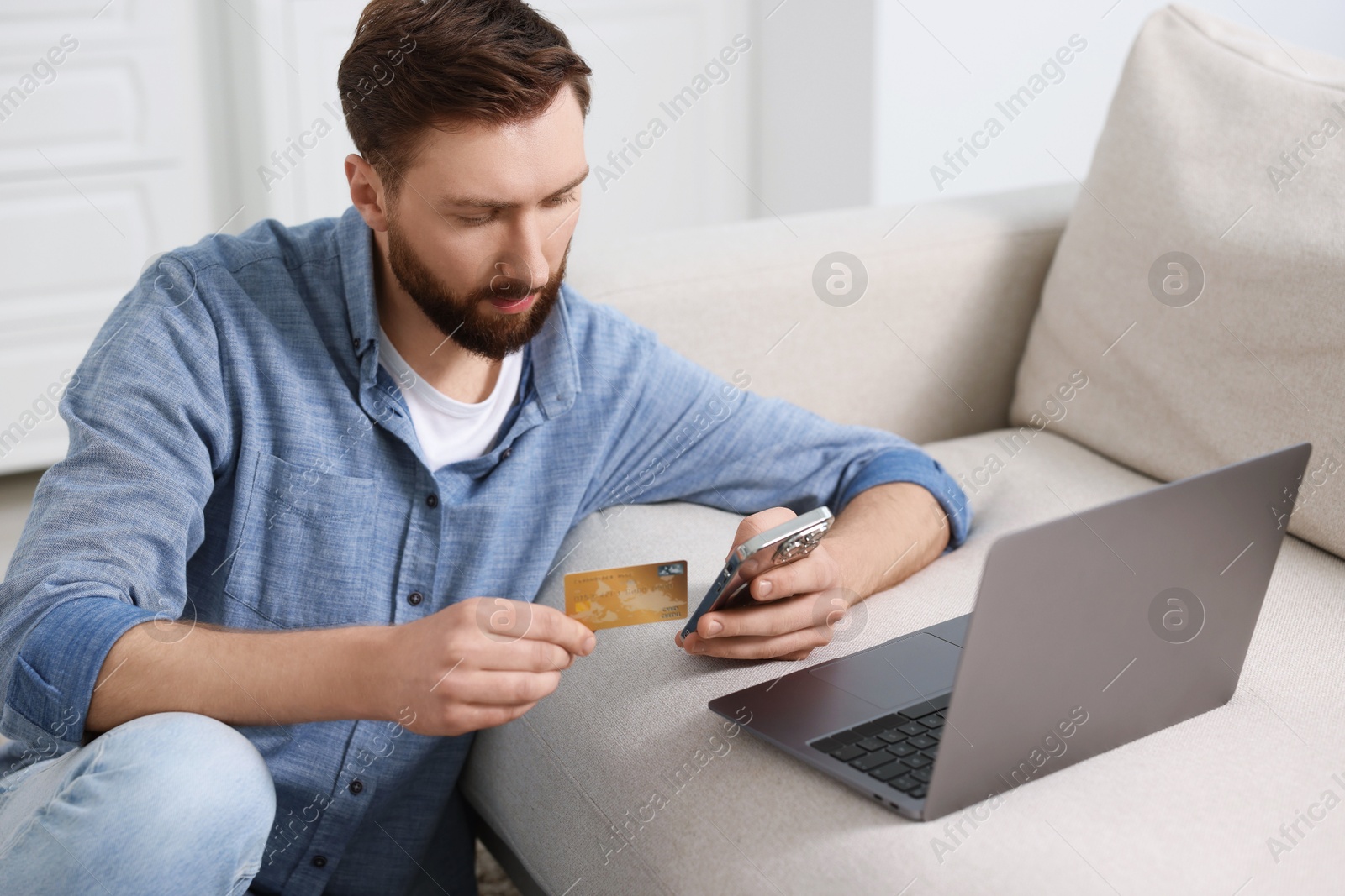 Photo of Online banking. Young man with credit card and laptop paying purchase at home