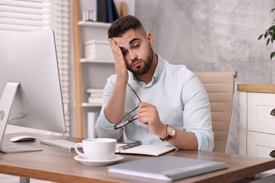 Photo of Overwhelmed man sitting at table in office