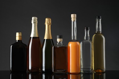 Photo of Bottles of different alcoholic drinks on table against gray background