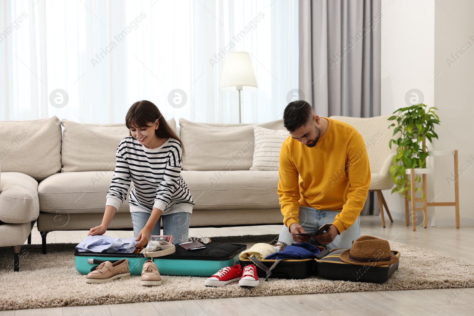 Photo of Couple packing suitcases for trip on floor at home