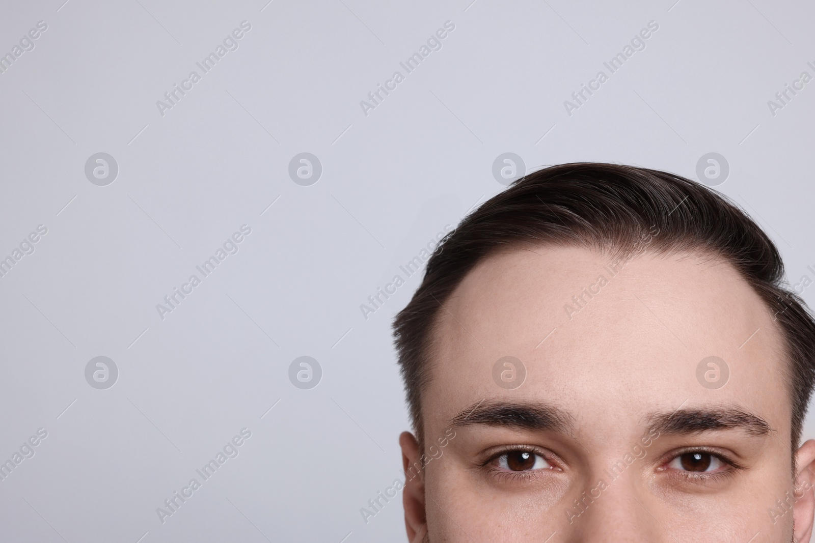 Photo of Baldness concept. Man with receding hairline on light grey background, closeup. Space for text