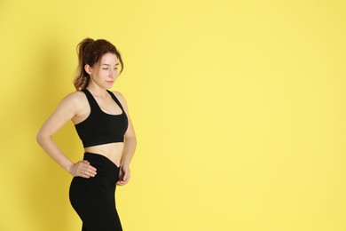 Woman with slim body posing on yellow background, space for text