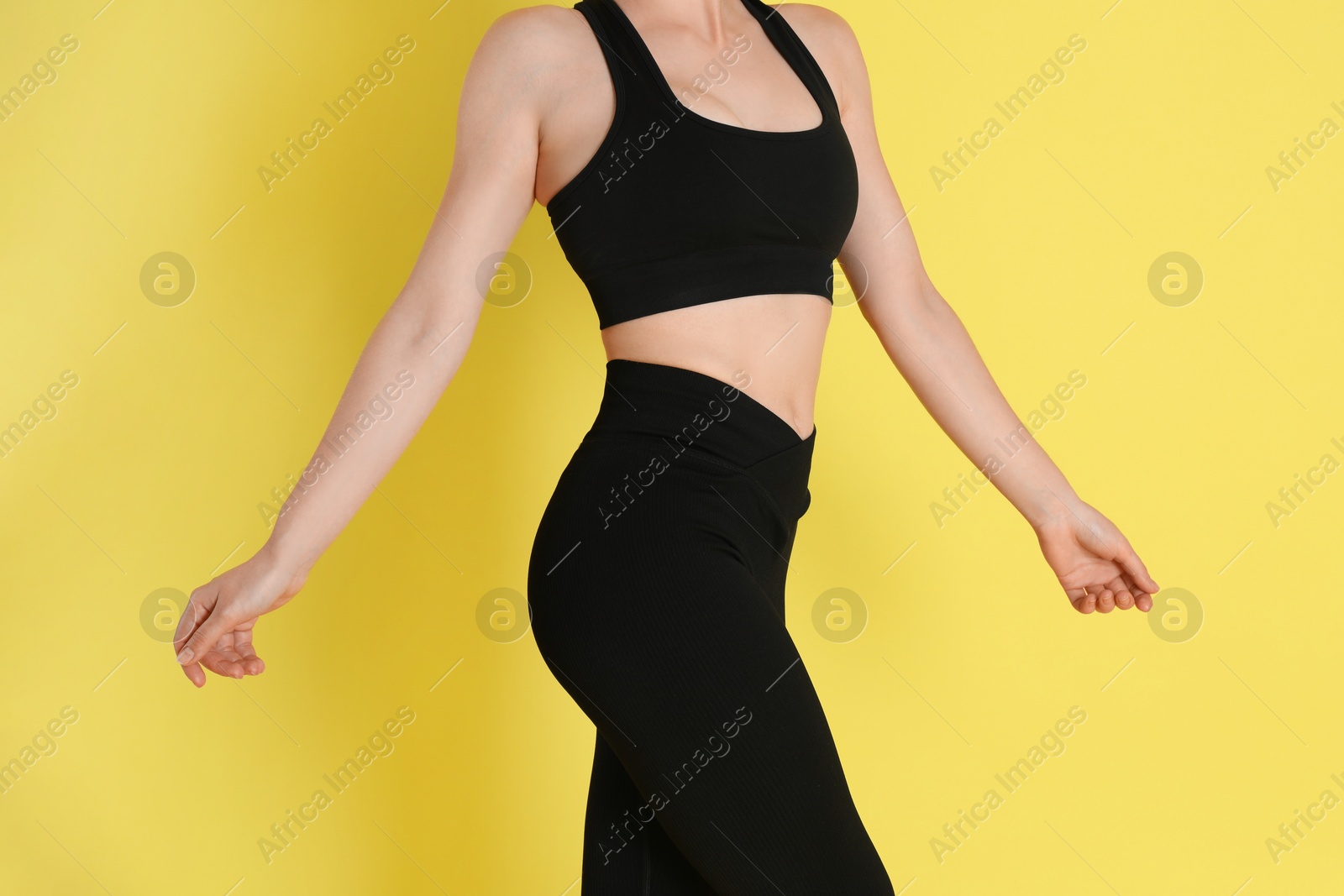 Photo of Woman with slim body posing on yellow background, closeup