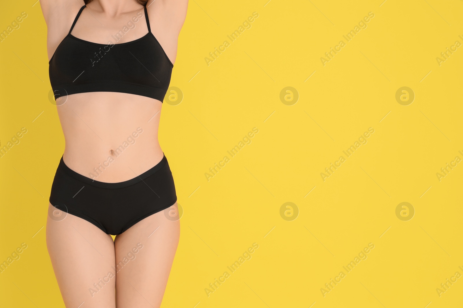 Photo of Woman with slim body posing on yellow background, closeup. Space for text