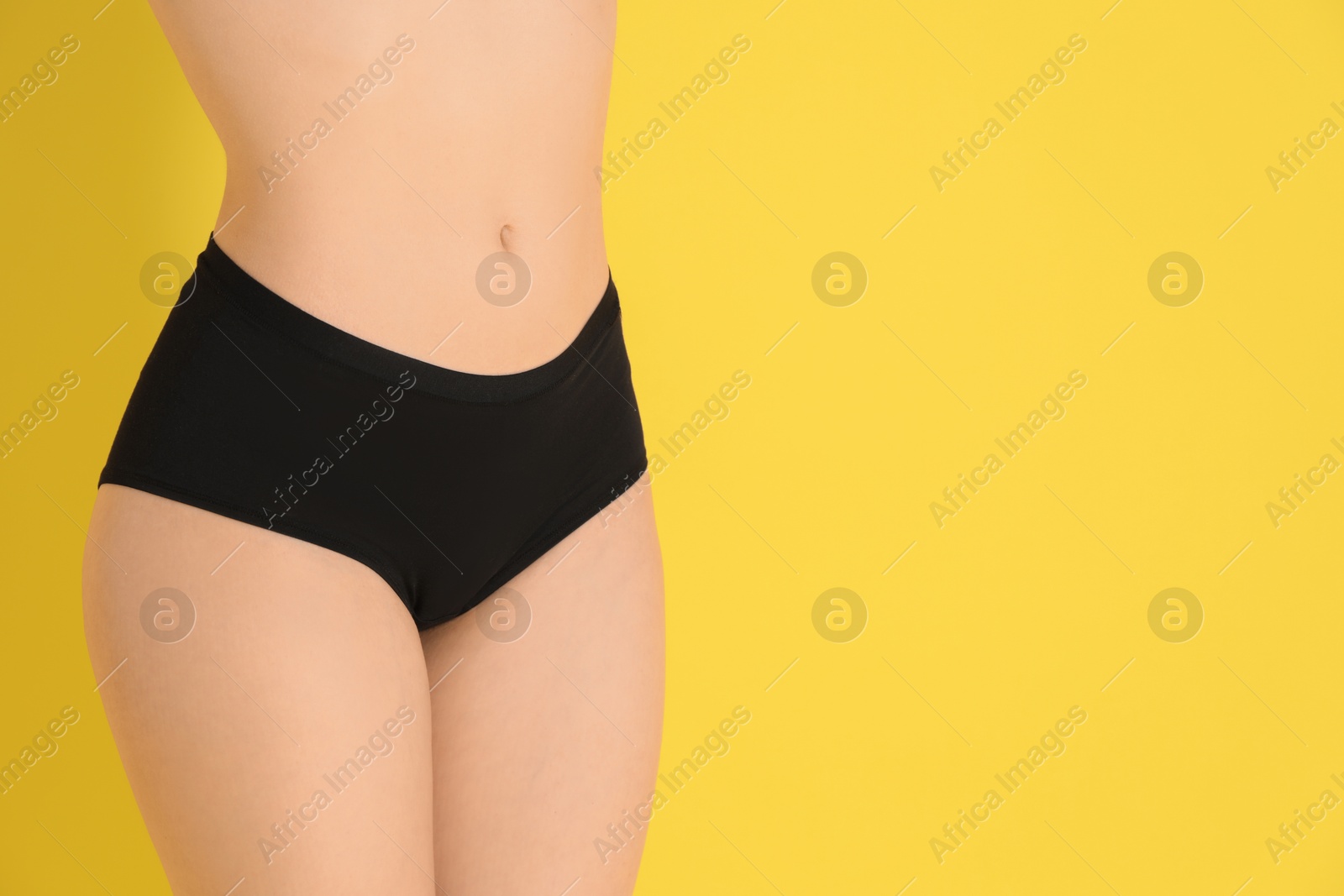 Photo of Woman with slim body posing on yellow background, closeup. Space for text