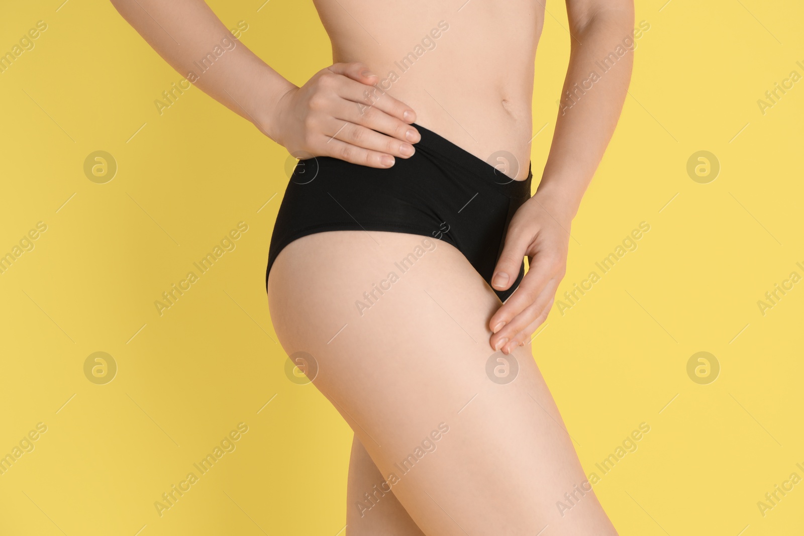 Photo of Woman with slim body posing on yellow background, closeup